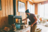 Man loads logs into wood-burning stove.
